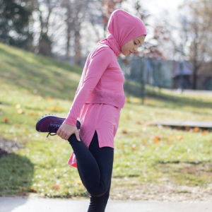 a woman wearing a sukoon athletic hijab while stretching