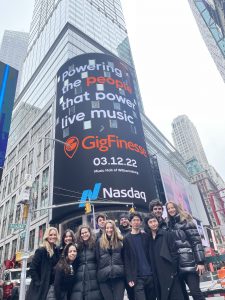 Photo of the GigFinesse team in front of the Nasdaq billboard in times swuare showing the GigFinesse logo
